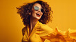 © Daniel - A radiant woman donning yellow sunglasses and a joyful smile stands confidently against an yellow indoor wall, exuding charm and style through her clothing and persona