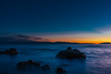 Canvas Print - Lake landscape with big stones at dark sunset, long exposure blurred motion