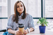 © BullRun - Stylish woman with takeaway beverage in office