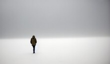 silhouette of a person, alone, standing in a vast empty and white space, isolation, vastness, loneliness