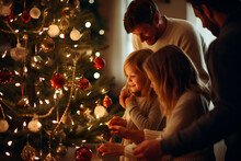 Father and daughters share a magical moment decorating their Christmas tree.