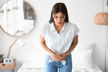 Poster - Young woman suffering from menstrual cramps in bedroom