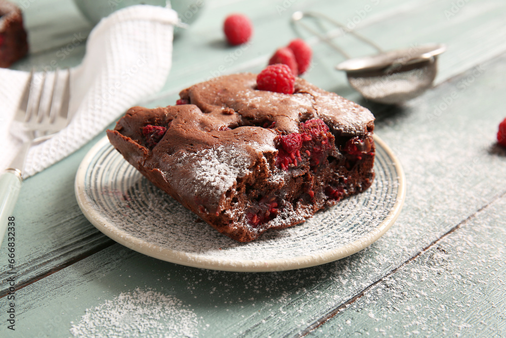Plate with piece of raspberry chocolate brownie on blue wooden table