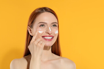 Sticker - Beautiful young woman with sun protection cream on her face against orange background, space for text