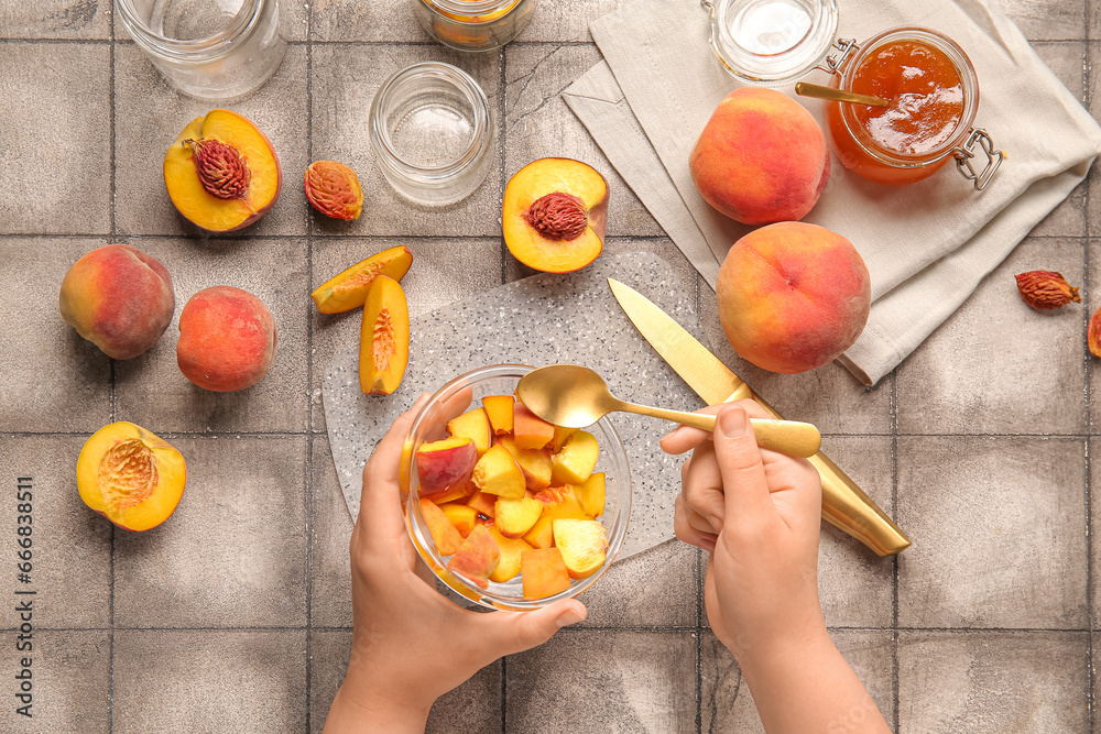 Woman preparing sweet peach jam on grey tile background
