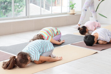 Poster - Group of little children practicing yoga with instructor in gym