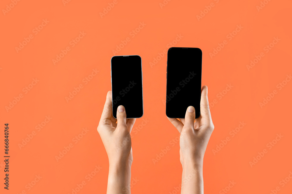 Woman with mobile phones on orange background