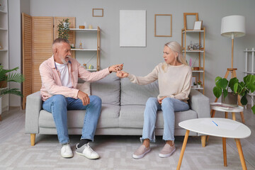 Canvas Print - Mature couple giving each other wedding rings at home. Divorce concept