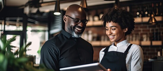 In a caf people communicate discuss and handle orders with the help of a tablet Waiters a black man and woman use technology for inventory stock checks and sales management