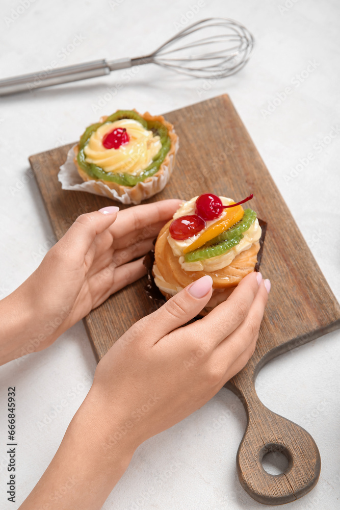 Female confectioner with tasty cakes on white background