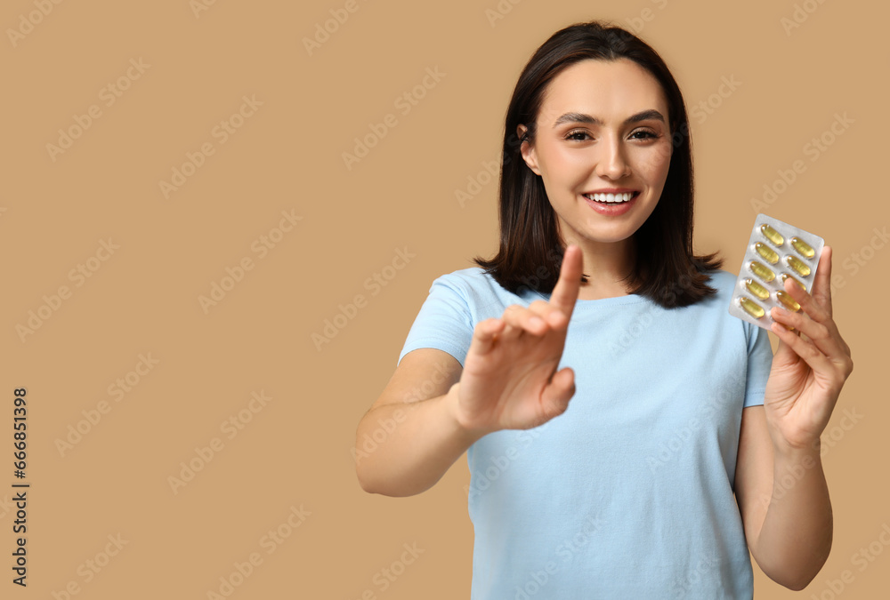 Pretty young woman with pills on brown background