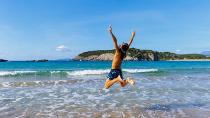 Wall Mural - Happy summer holiday- young child jumping in the air on the beach