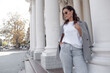 © Вероника Зеленина - A beautiful woman walking in the street of the city. A business woman looking sidesways. the female wearing the style basic outfit, jeans, blazer, sunglasses and white shirt
