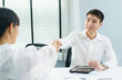 © DG PhotoStock - Two young Asian businesspeople having a handshaking together in office, man and woman shaking hand after finished their works.