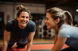 A happy female coach is training sportswoman in a gym who is exercising