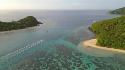 Wall Mural - boat passes through channel between tropical islands in fiji at sunset