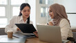 © bongkarn - A beautiful Asian businesswoman is working with an Asian-Muslim female colleague in the meeting room