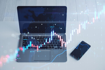 Poster - Close up of laptop and cellphone with glowing candlestick forex chart on blurry background. Trade, finance and growing market concept. Double exposure.