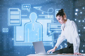 Poster - Thoughtful young european businesswoman sitting on desktop with creative blue devices hologram on blurry office interior background. Digital marketing, social network and online service concept.