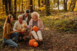 © bernardbodo - Two family generations sitting in the woods holding pumpkins