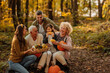 © bernardbodo - Happy family sitting in the woods holding pumpkins