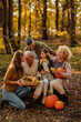 © bernardbodo - Family sitting in the woods holding pumpkins