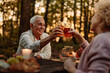 © bernardbodo - Elderly couple raising a toast with juice in the woods