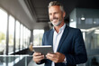 © Danny - portrait of professional businessman standing in office. Happy middle aged businessman ceo wearing suit standing in office using digital tablet.