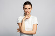Young beautiful girl making silence gesture, asking not tell anyone secret, on light grey studio background
