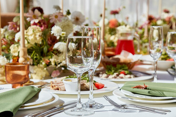 A sophisticated tableau arrangement on the table, adorned with candles and delicately placed flowers beneath the play of shadows. A wedding style reminiscent of Provence aesthetics