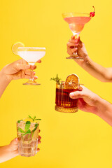 Poster. Variations of alcohol drinks. Hands with set of classic glasses of cocktails against over colorful studio background.