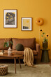 Interior design of yellow living room interior with mock up poster frame, brown sofa, wooden coffee table, slippers, green rug, basket, orange lamp and personal accessories. Home decor. Template.