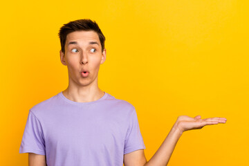 Wall Mural - Handsome young man in casual clothes presenting an idea with hand to copy space isolated on yellow background