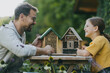 © Halfpoint - Father with daughter making bug hotel, or insect house outdoors in the garden. Girl learning about insects, garden ecosystem and biodiversity.