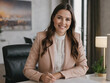 © niki spasov - Smiling young businesswoman sitting on a desk in his office. Property sales manager. Generative Ai