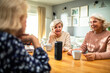 © Marko Geber - Senior female friends listening to music on a speaker at home