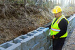 © ungvar - As construction worker mounting retaining wall from, concrete block to ensure its proper placement