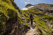 © Guzel - A man with a backpack climbs a scenic rocky trail to a mountain peak, Austria