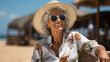 Mature woman happy and enjoying vacation on the beach. Older woman with a beach hat, sunglasses and a flowered shirt sunbathing in a Caribbean hotel. Beautiful and elegant woman of about 60 years 