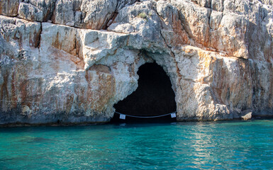 Wall Mural - Cave in the cliff, in the sea. There is a sign saying in Turkish, 