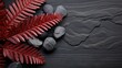 Vivid red fern leaves beautifully arranged beside smooth grey zen stones on a textured slate