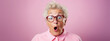 Studio portrait of elderly granny wearing glasses, pink background, shocked and surprised expression