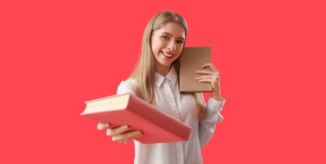 Wall Mural - Beautiful young woman with books on red background