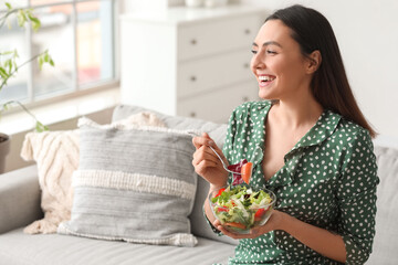 Wall Mural - Young woman eating vegetable salad at home