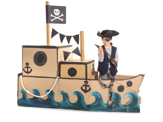 Poster - Cute little pirate playing with sword in cardboard ship on white background