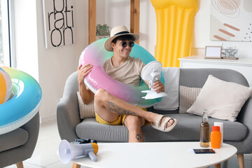 Poster - Young man with beach accessories ready for summer vacation at home