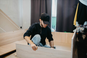Wall Mural - man assembling furniture wooden cabinet at home