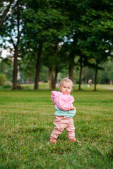 Wall Mural - Cute caucasian kid baby sitting on the grass in a jacket