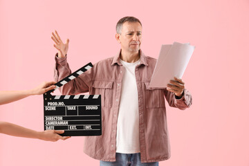 Poster - Mature actor reading film script and hands with clapperboard on pink background