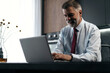 © opolja - Senior man checking working on laptop in kitchen at home